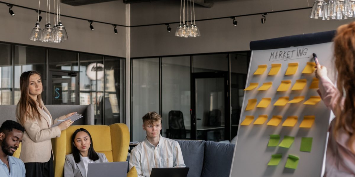 A small team collaborates at a whiteboard, strategizing their online marketing efforts.