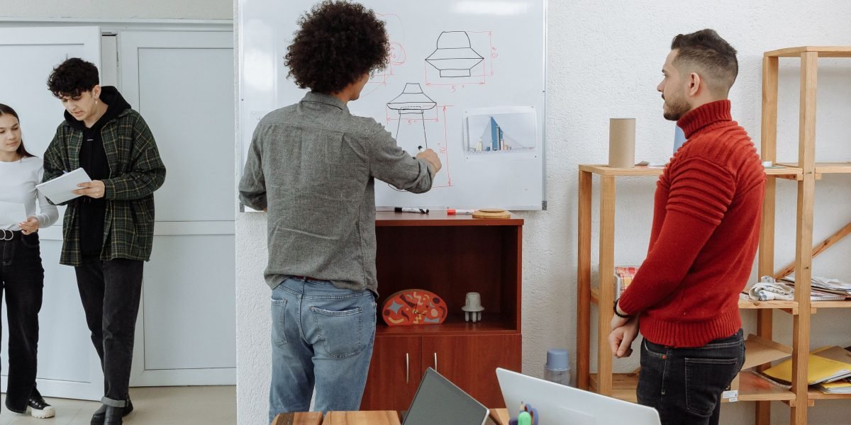 Designers actively collaborating, sketching ideas and communicating concepts on a whiteboard.
