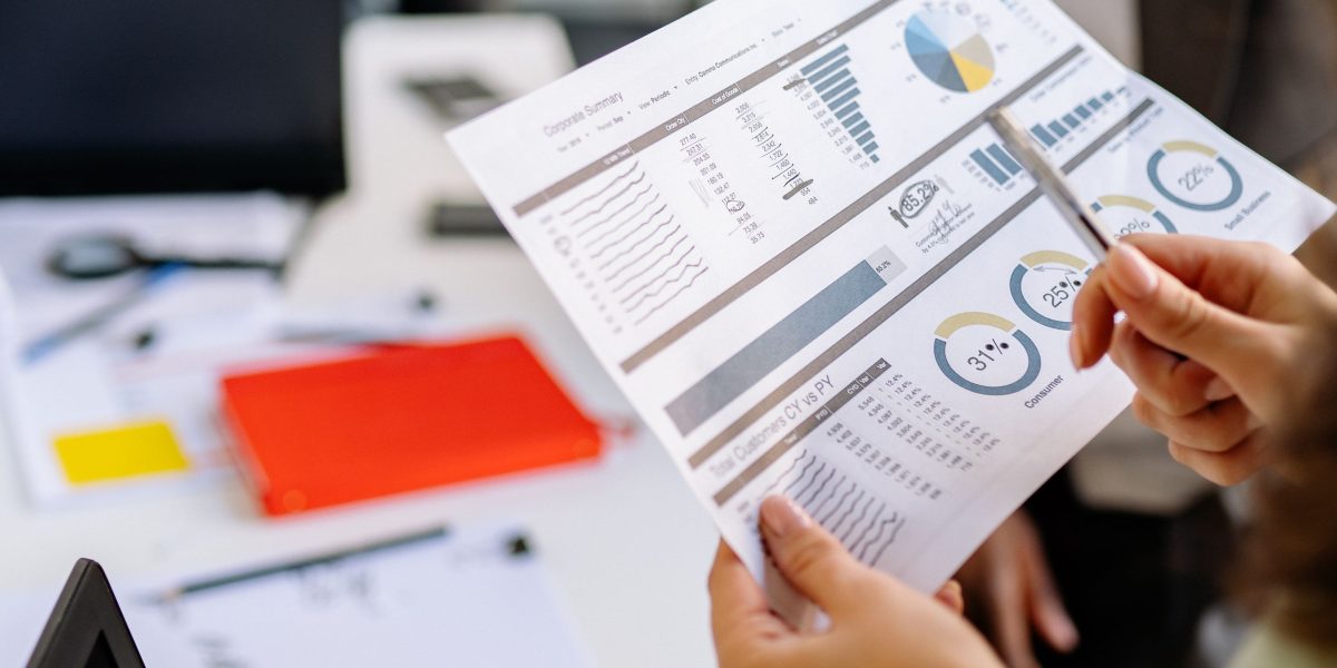 A person intently reviewing performance reports, likely analyzing sales data or marketing analytics.
