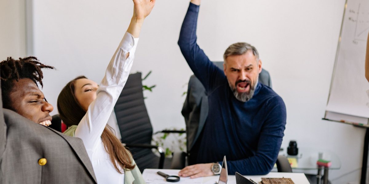 A diverse team of people high-fiving or cheering in an office setting, celebrating success. A small business team celebrates a successful advertising campaign and business growth.