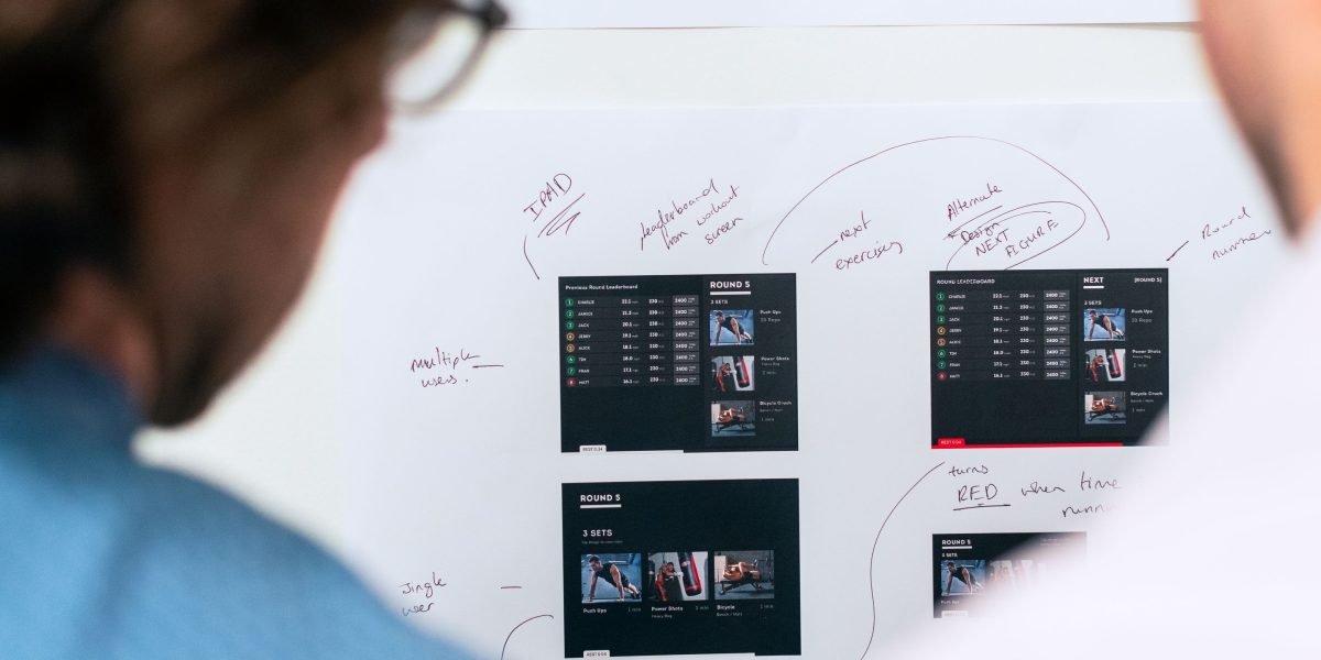 A design team collaborates, sketching ideas on a whiteboard to refine layout and spacing.