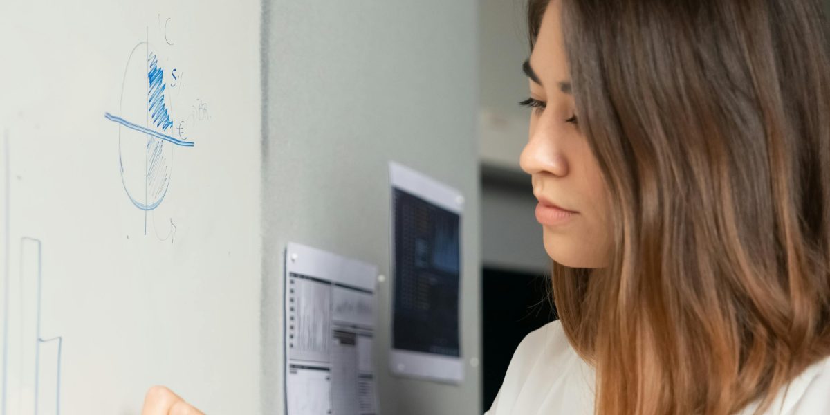 A person contemplating a strategy on a whiteboard, representing thoughtful planning.